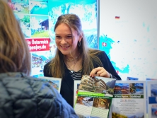 Prospektpräsentation am Messestand Urlaub in den Alpen