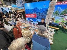 Prospektpräsentation am Messestand Urlaub in den Alpen
